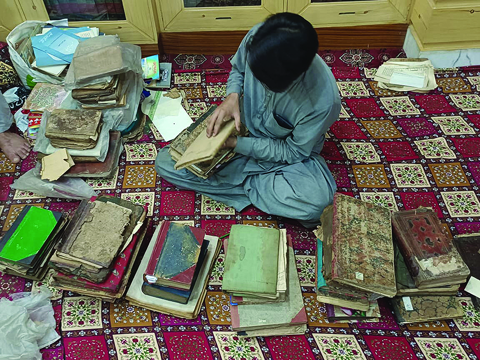 Archival technician Shoaib Awan examining rare manuscripts at the Amir Shah Qadri Monastery Library.